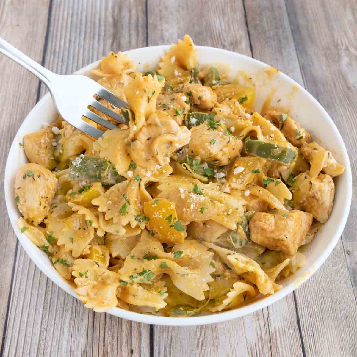 creamy cajun chicken pasta in a white bowl with a fork in it.